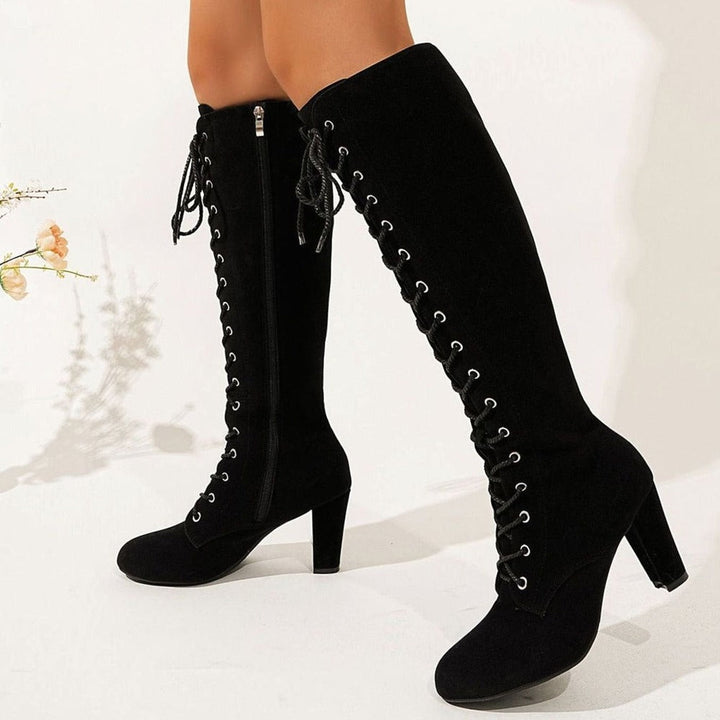 Black lace-up knee-high boots with block heel, worn