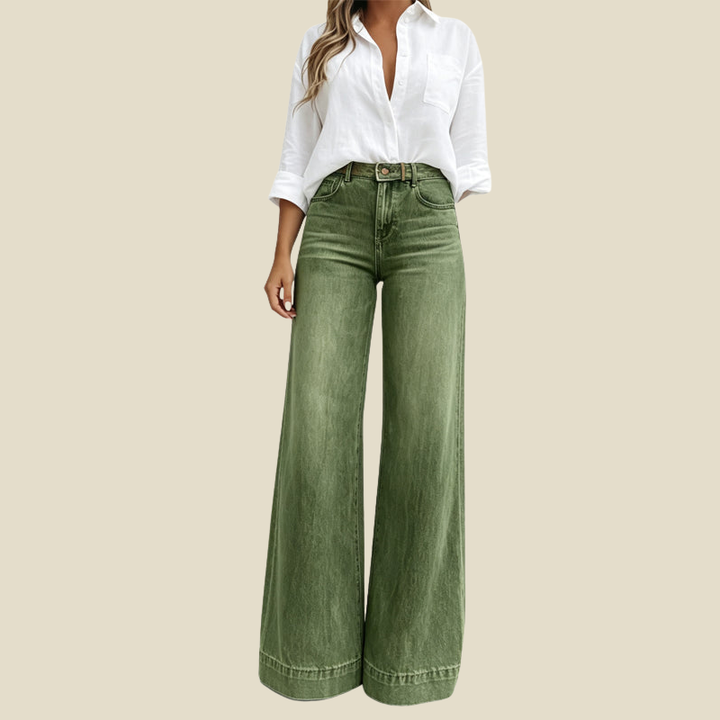 A woman wears a white button-up shirt with green wide leg denim trousers, shown from the front against a plain beige background.