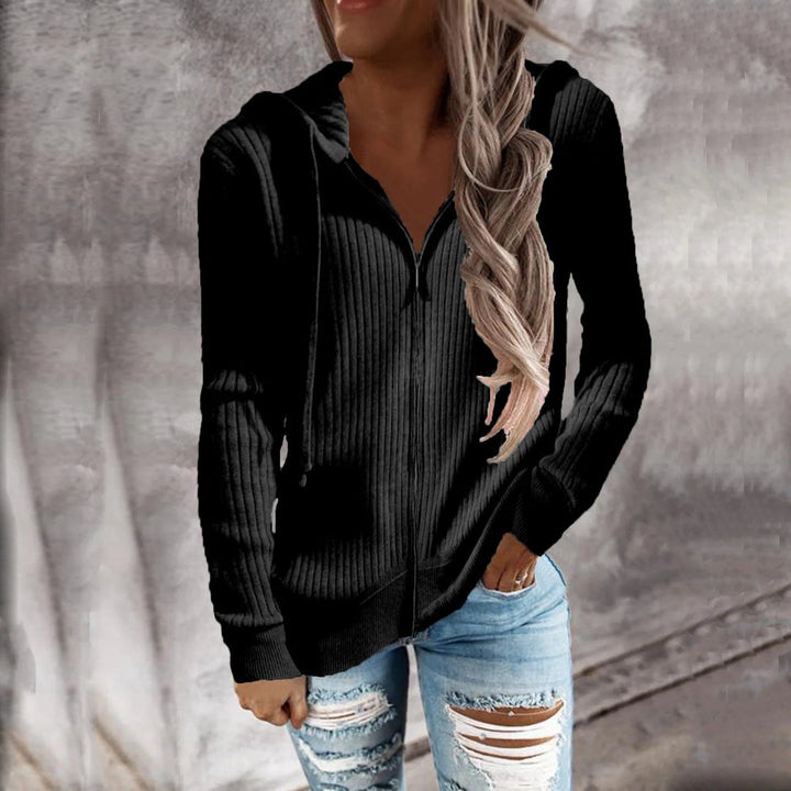 Woman wearing a black ribbed zip-up hoodie with ripped jeans, one hand in her pocket | Grace Aura