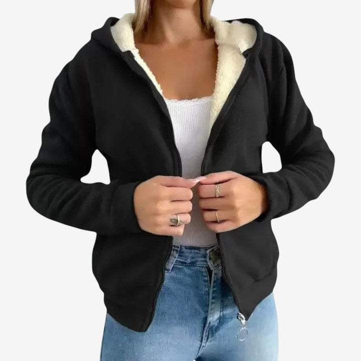 Woman wearing a black fleece jacket with cream sherpa lining over a white top and jeans | Grace Aura