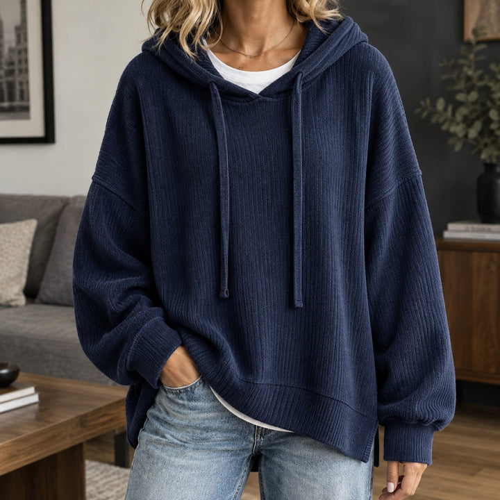 Woman wearing a navy knit hoodie over a white T-shirt, one hand in her pocket | Grace Aura