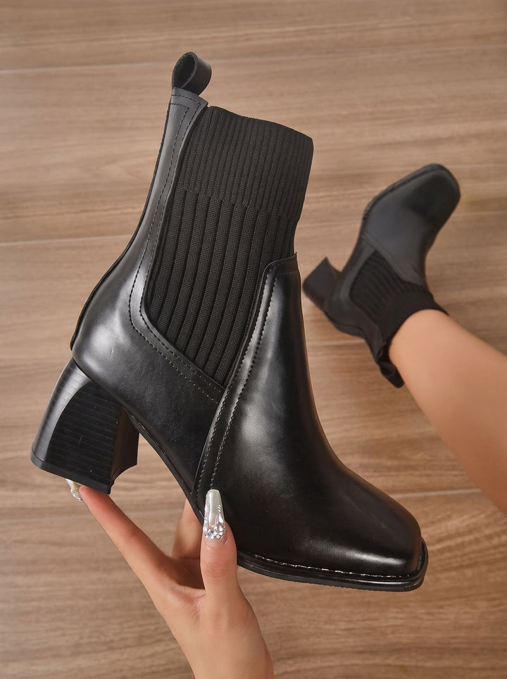 Black knit shaft ankle boot with block heel, held in hand