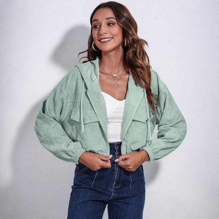 Woman wearing a mint green cropped cord jacket with hood over a white top | Grace Aura