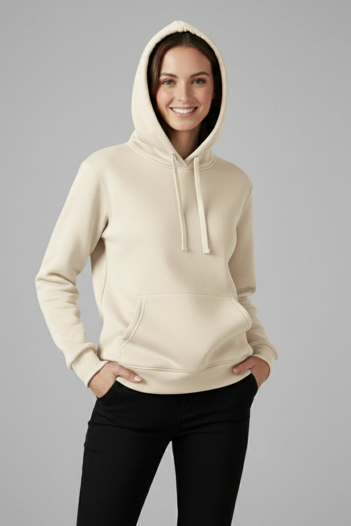 Woman wearing a cream pullover hoodie with drawcords, hands in her trouser pockets | Grace Aura