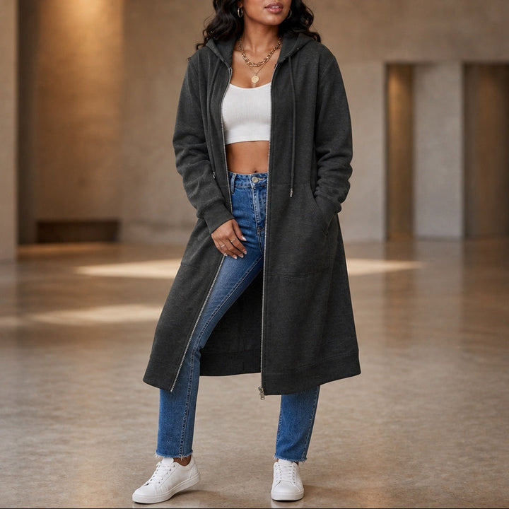 Full-length view of a woman in a charcoal longline zip-up hoodie worn open with jeans, one hand in a pocket | Grace Aura