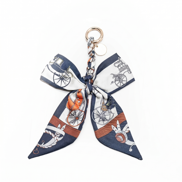 Navy and white carriage-print fabric bow keychain with metal chain, laid flat | Grace Aura