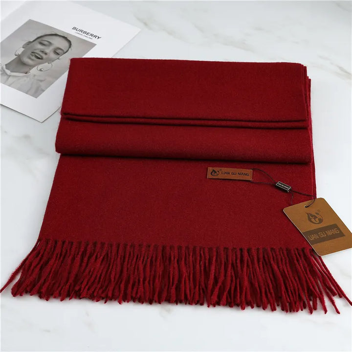 Folded burgundy fringed scarf with tag, shown flat on marble surface | Grace Aura