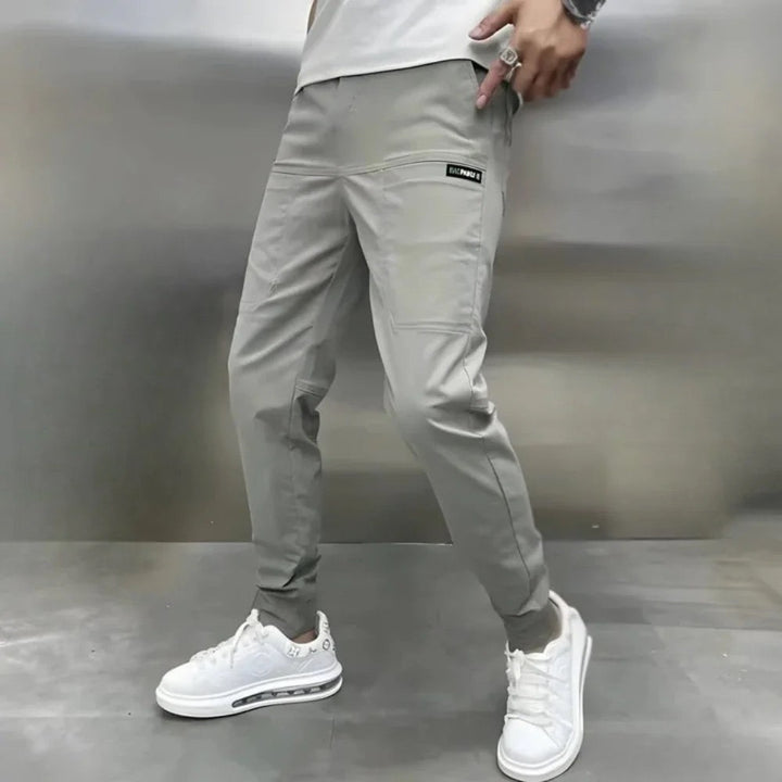 Man wearing light gray tapered cargo pants with white sneakers, side view | Grace Aura