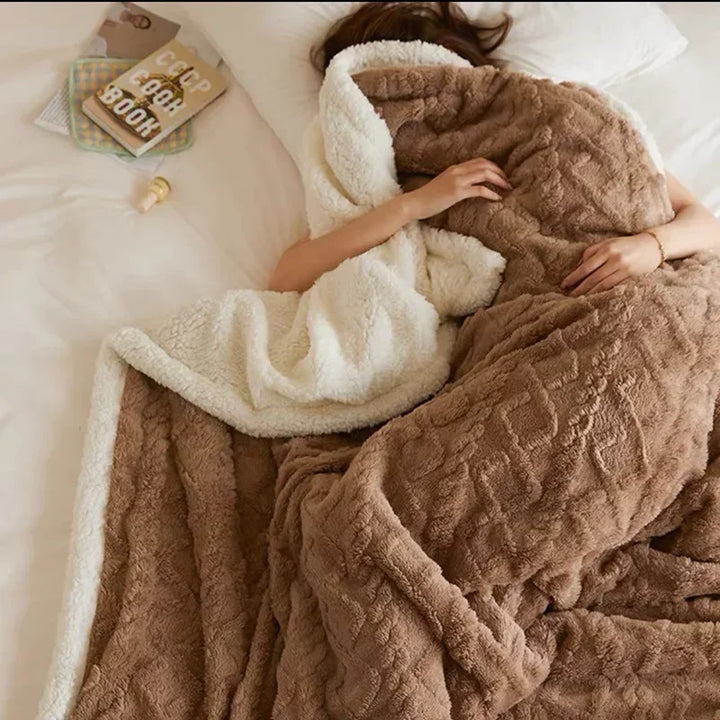 Brown quilted sherpa blanket with white trim, person sleeping wrapped underneath | Grace Aura