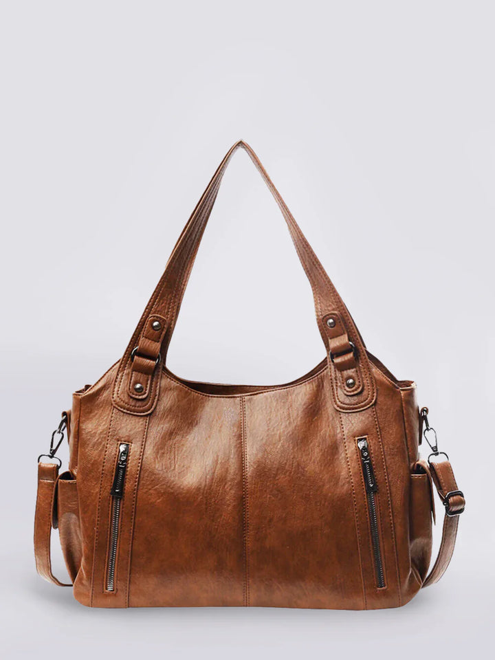 Brown vegan leather shoulder bag with front zippers, shown standing upright | Grace Aura