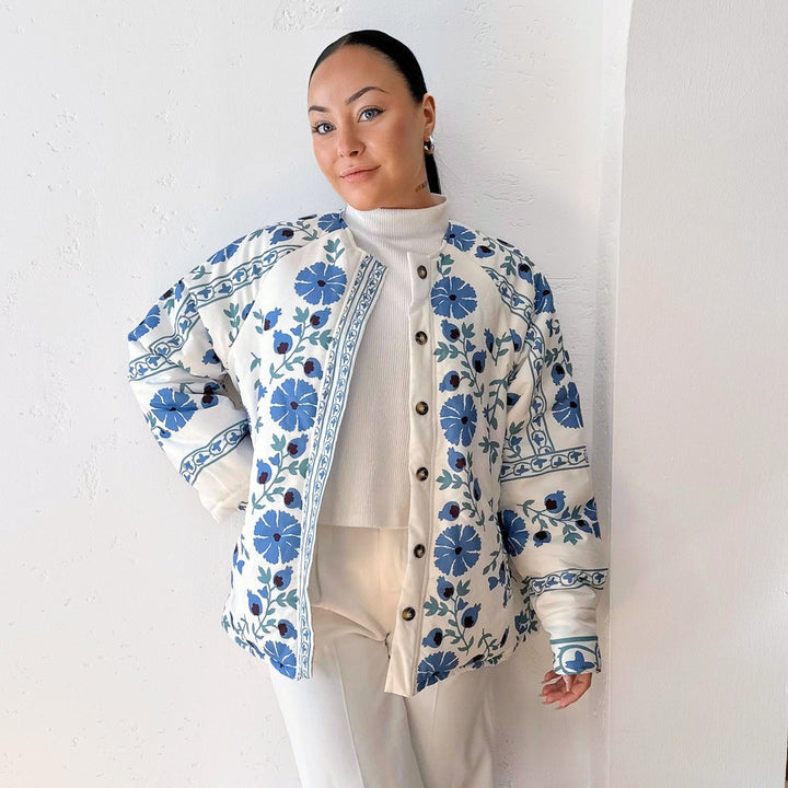 Woman wearing white quilted jacket with blue floral print, buttoned, worn open | Grace Aura
