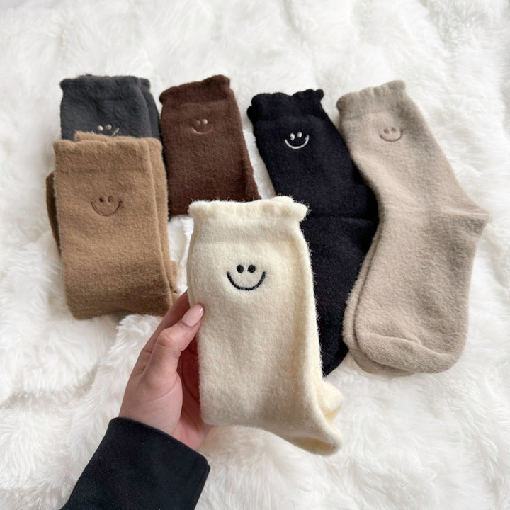 Fuzzy smiley face crew socks, six pairs, hand holding cream pair | Grace Aura