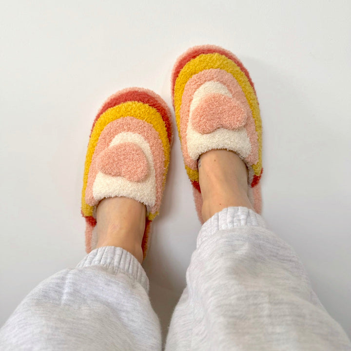 Worn fuzzy slippers with pink, yellow, cream heart pattern, top view | Grace Aura