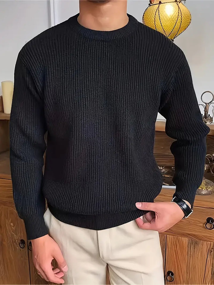 Black ribbed knit crew neck sweater worn by man, paired with beige trousers | Grace Aura