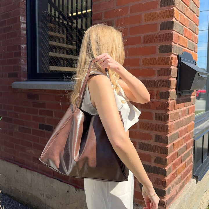 Bronze faux leather tote bag worn on shoulder by woman outdoors | Grace Aura