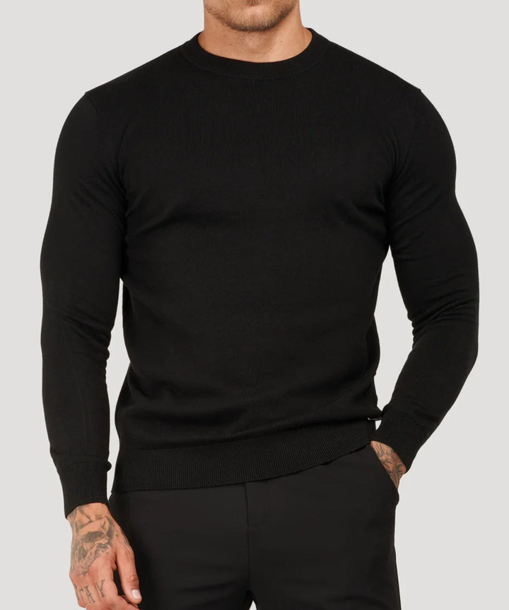 Black long-sleeve crew neck sweater worn by man, paired with black trousers | Grace Aura