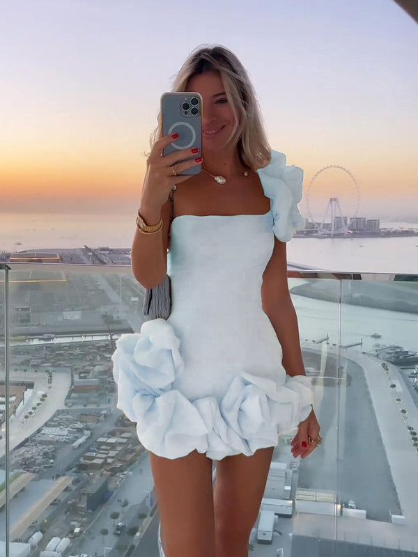 White one-shoulder ruffled mini dress worn by woman on balcony | Grace Aura