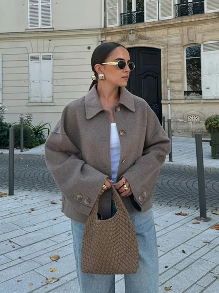Woman wearing oversized brown wool jacket with woven handbag outdoors | Grace Aura