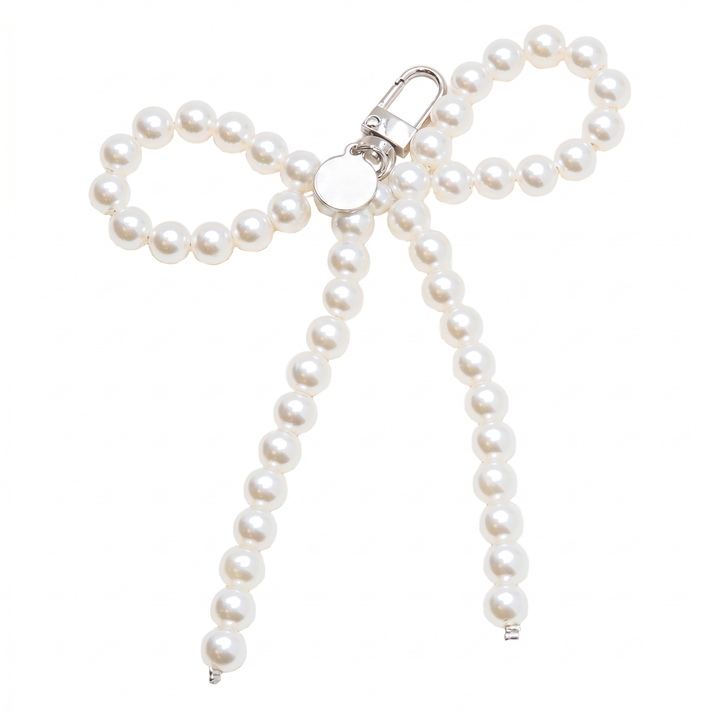 White pearl bow-shaped bag charm with silver clasp, laid flat | Grace Aura