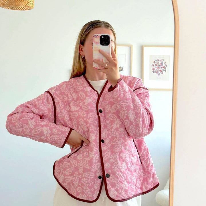 Pink quilted floral jacket with maroon trim, worn by woman indoors | Grace Aura