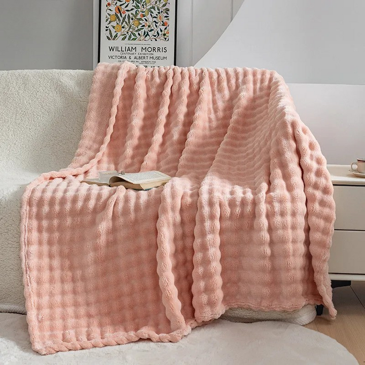Pink checkered plush blanket draped over armchair with book | Grace Aura