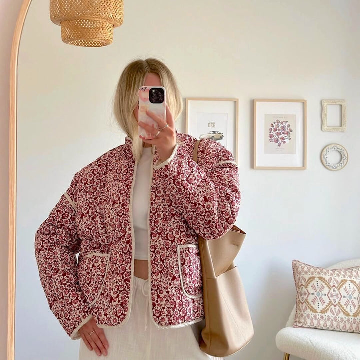 Woman wearing red floral quilted jacket with cream trim, mirror selfie | Grace Aura