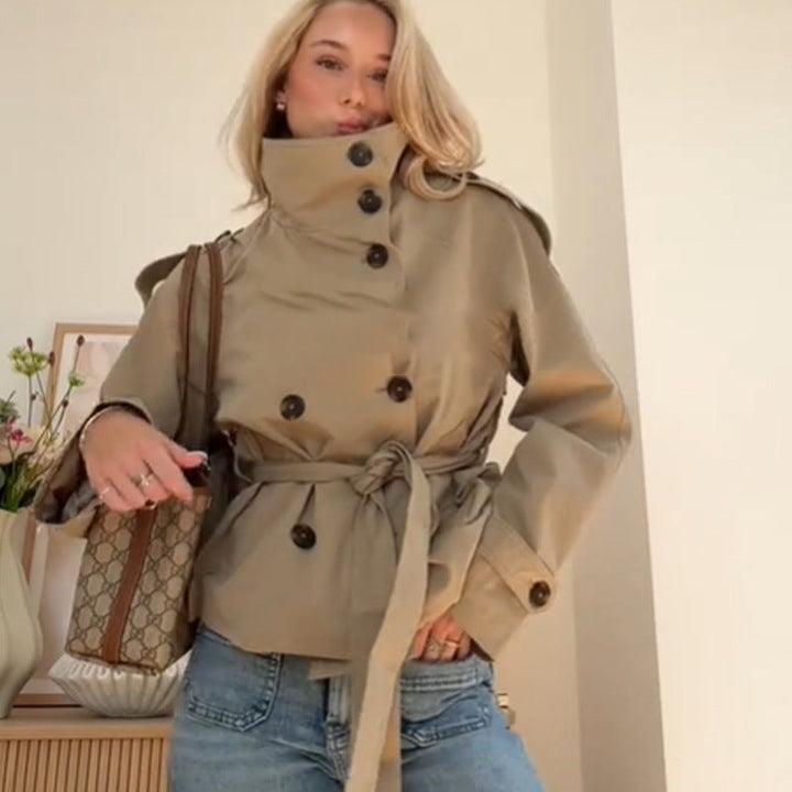 Woman wearing khaki belted double-breasted trench coat with high collar, indoors | Grace Aura