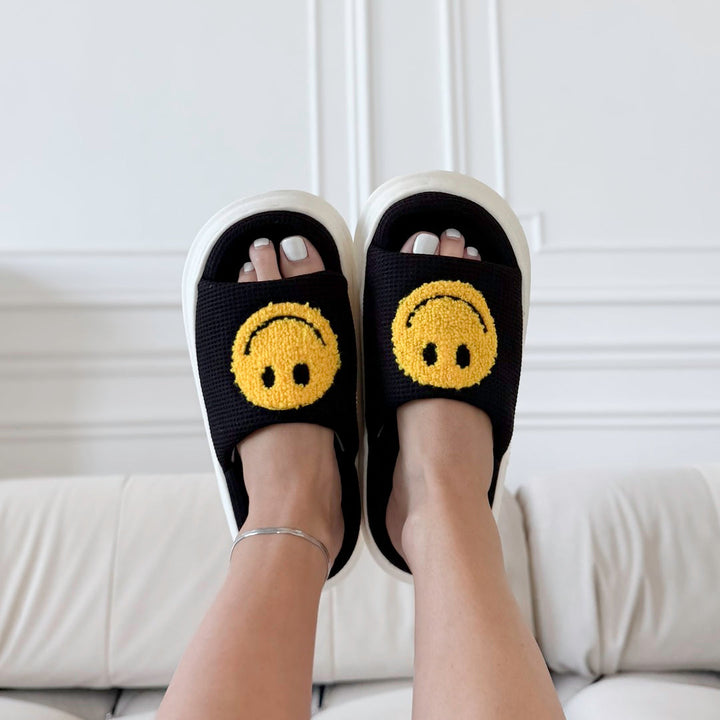 Black slide sandals with yellow smiley face patches, worn on feet | Grace Aura