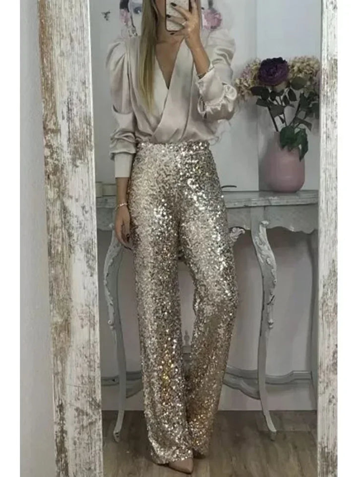Woman wearing gold sequin flared trousers with white blouse, mirror reflection | Grace Aura