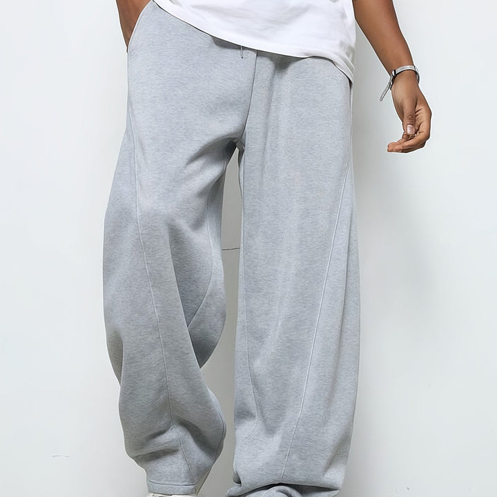Man wearing baggy grey drawstring sweatpants with white top, front view | Grace Aura