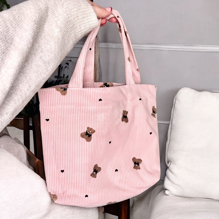 Pink striped corduroy tote bag with teddy bear print, held by hand | Grace Aura