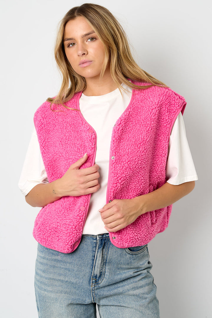 Woman wearing pink teddy fleece vest over white t-shirt and jeans | Grace Aura