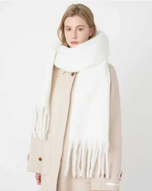 White fringed chunky knit scarf worn by woman over beige coat | Grace Aura