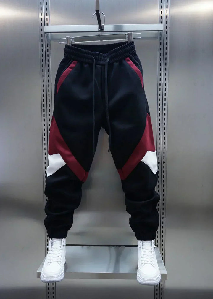 Black joggers with red and white geometric panels, displayed on hanger | Grace Aura