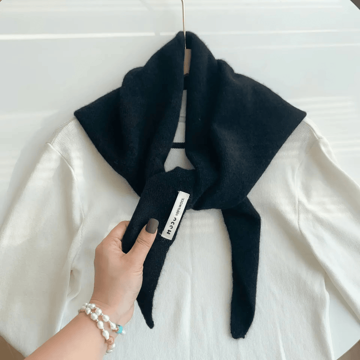 Black knitted triangle scarf tied over white shirt, held by hand | Grace Aura