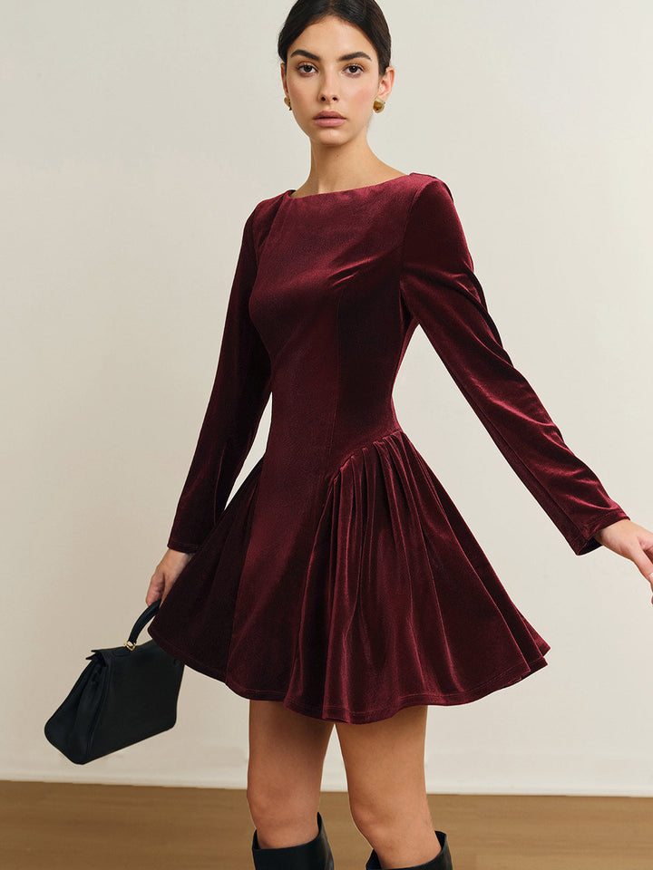 Woman wearing burgundy velvet long sleeve dress with pleated flared skirt | Grace Aura