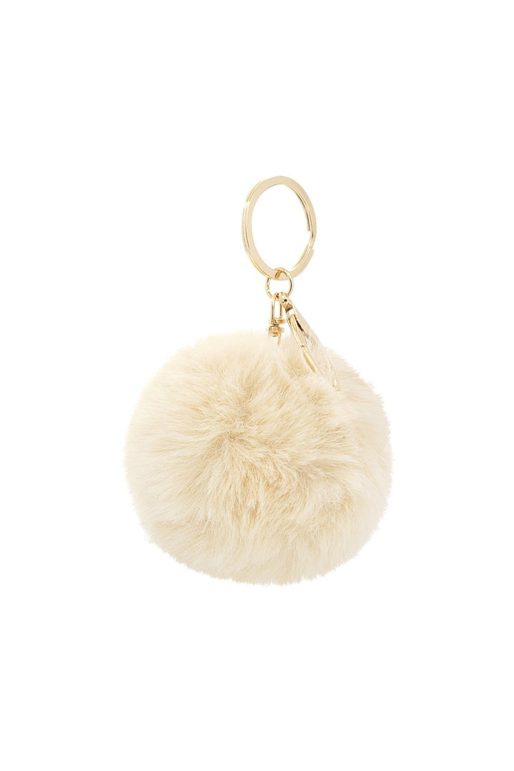 Cream faux fur pom pom keychain with gold ring hardware, flat lay | Grace Aura
