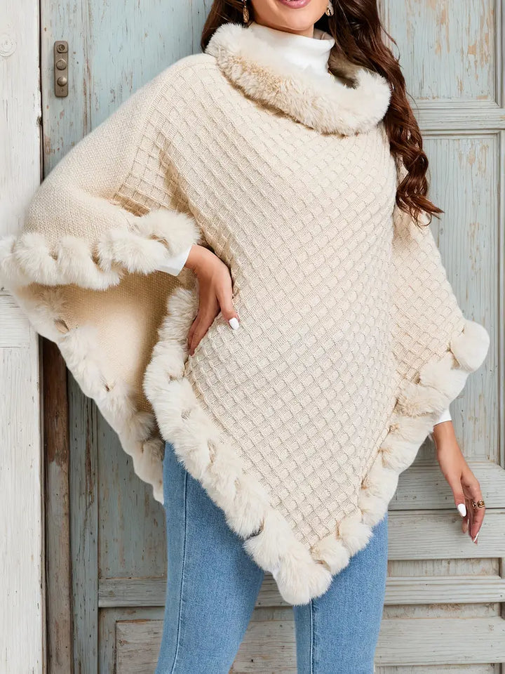 Cream knitted poncho with faux fur trim, worn by woman outdoors | Grace Aura
