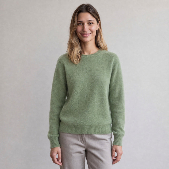 Woman wearing sage green crew neck jumper with grey trousers, smiling | Grace Aura