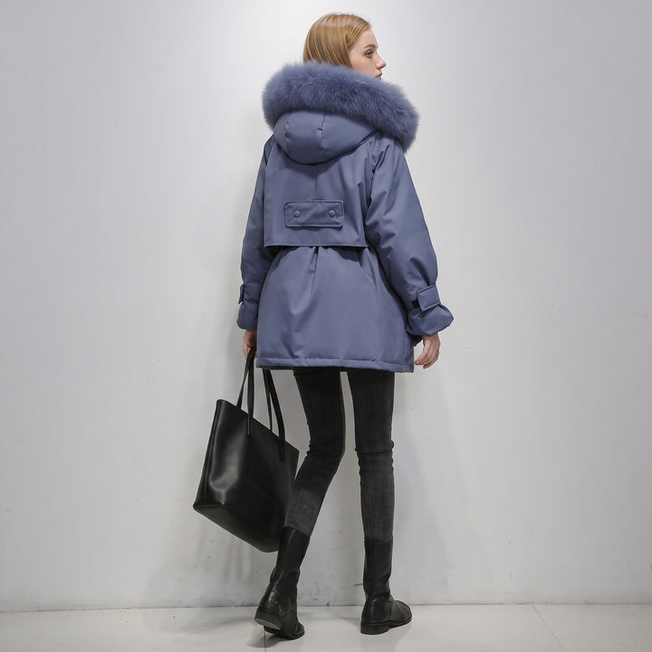 Woman wearing blue-gray puffer parka with fur-trimmed hood, carrying black tote bag | Grace Aura