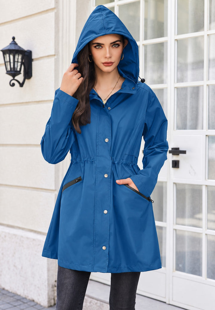 Blue parka worn closed with the hood up and one hand in a zipped pocket
