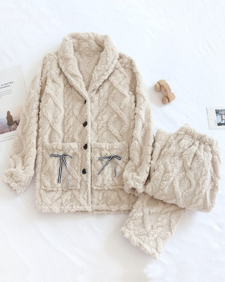 Cream fleece pyjamas with shawl collar, button-up top and bow pockets, flat lay
