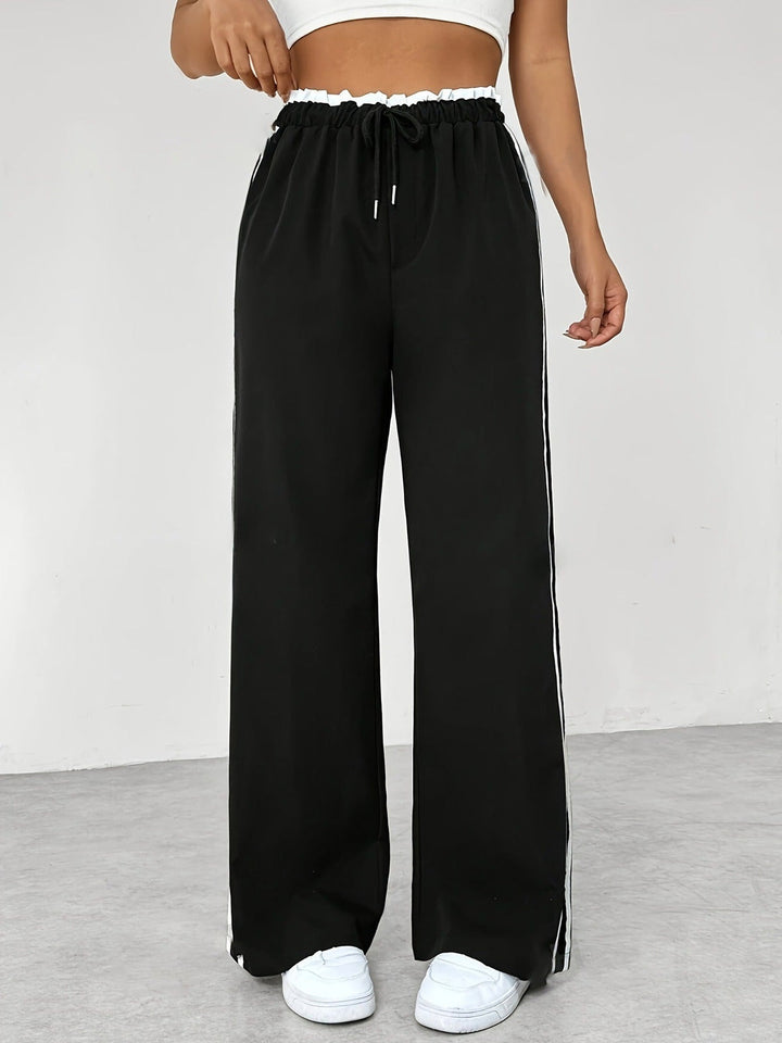 Wide-leg joggers with white side stripes in black, worn, front view