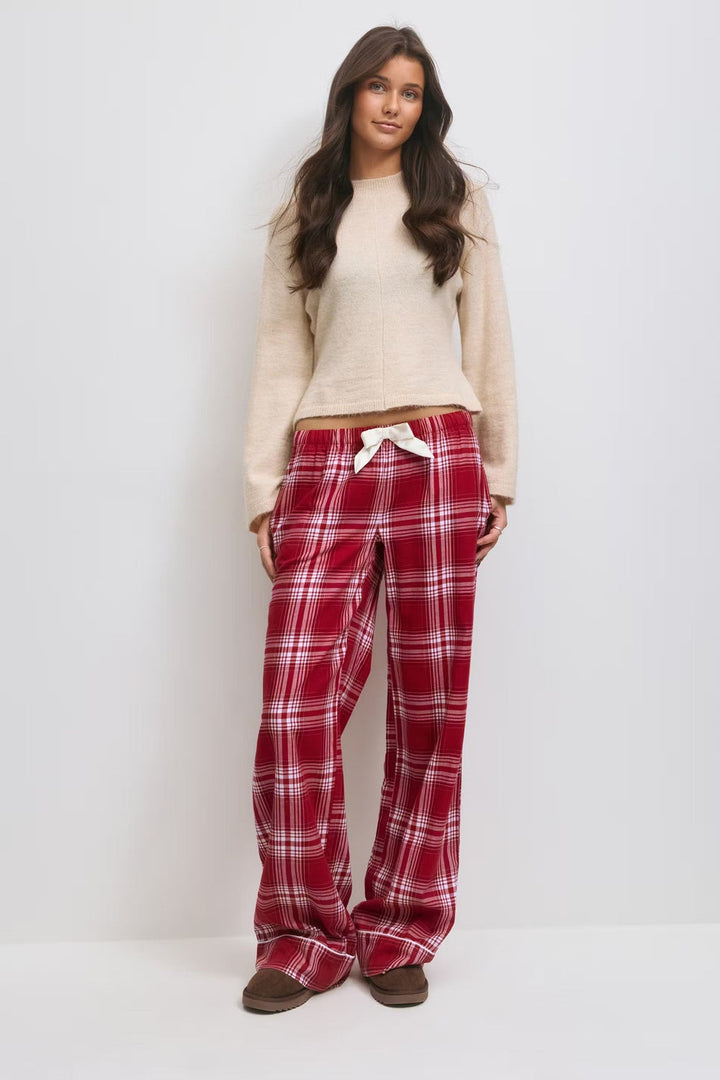 Cream jumper and red tartan flannel pyjama trousers with a bow at the waist, front view