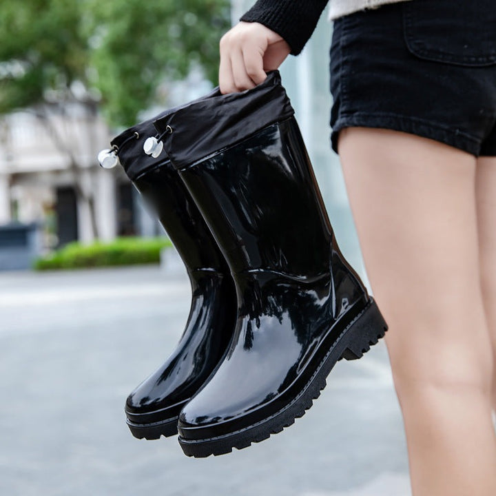 Wellies with drawstring fabric cuff in black, held in the hand