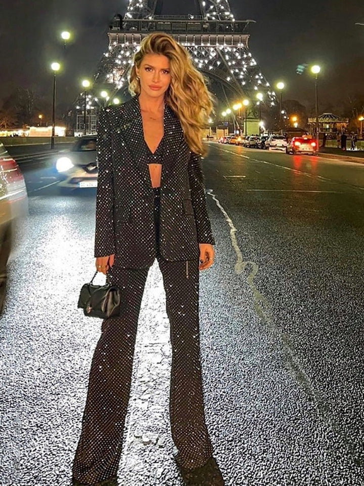 Sparkly three-piece trouser suit with rhinestone blazer, bralette and flared trousers in black, worn on an evening out