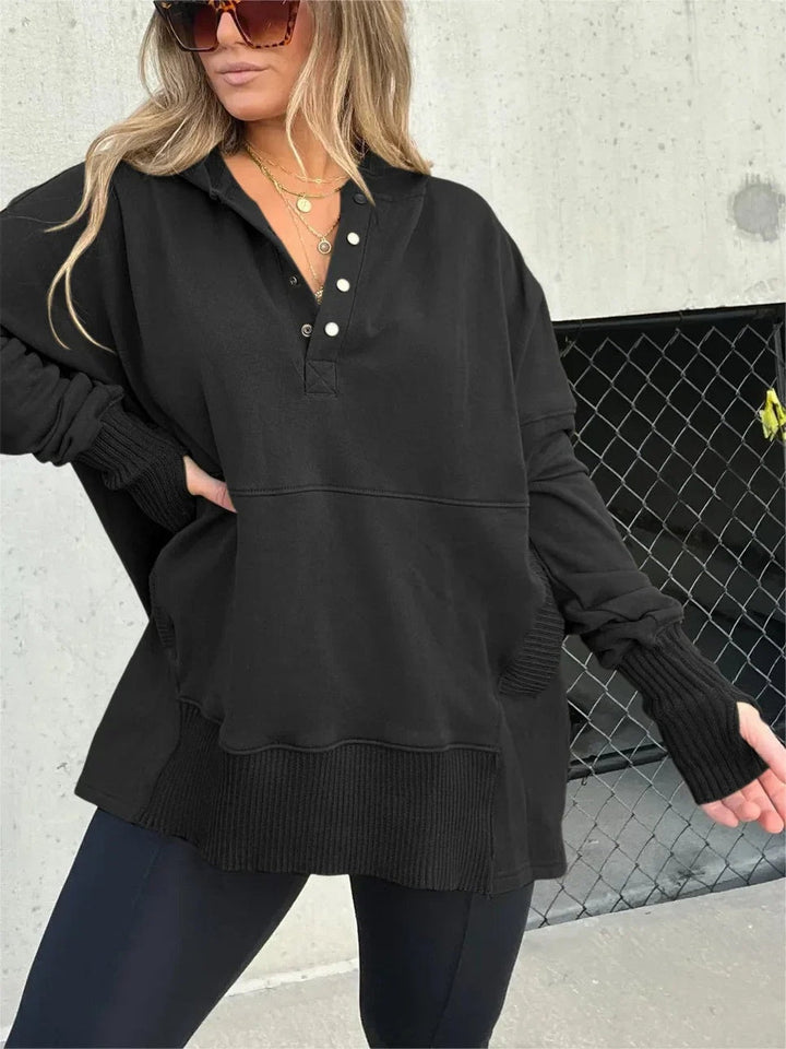 Woman wearing a black oversized button-neck hoodie, one hand on her hip | Grace Aura