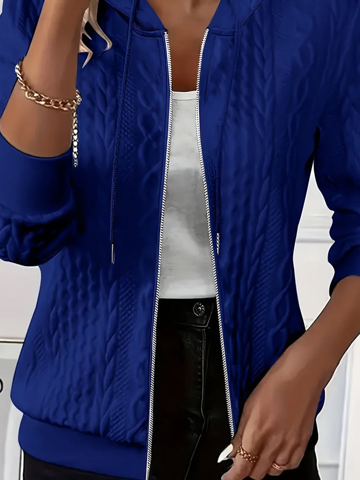 Woman wearing an open royal blue zip-through hoodie with a textured pattern over a white top | Grace Aura
