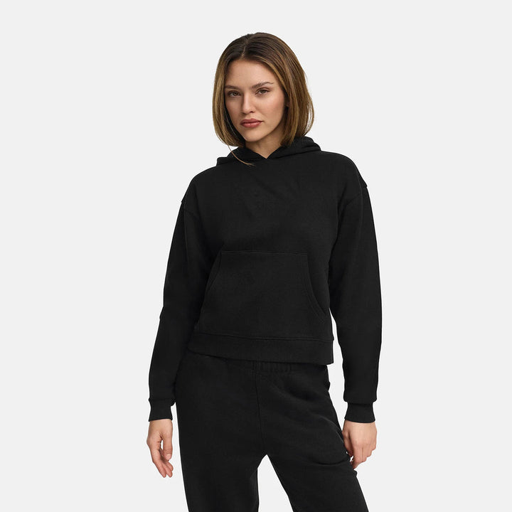 Woman wearing a black relaxed-fit hoodie with a kangaroo pocket and matching trousers | Grace Aura