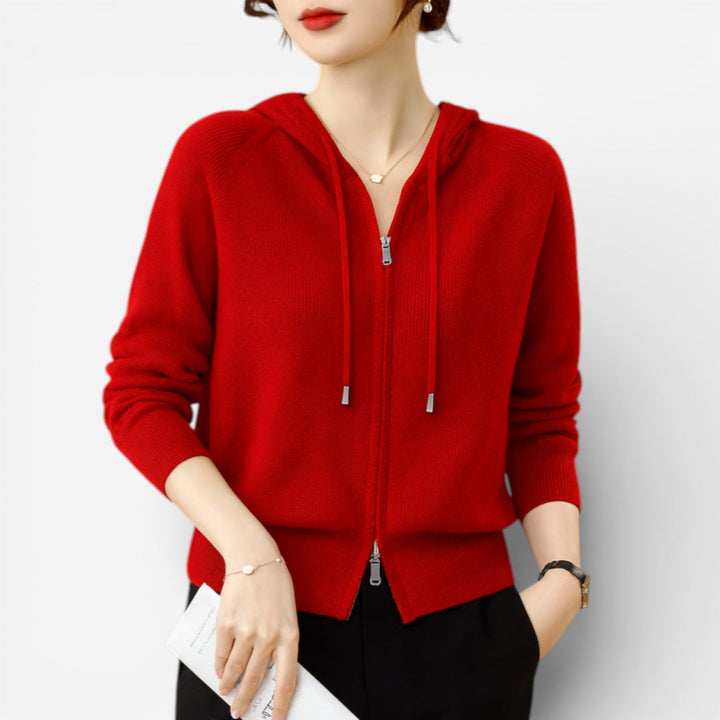 Woman wearing a red knitted hooded cardigan with a two-way zip and black trousers | Grace Aura